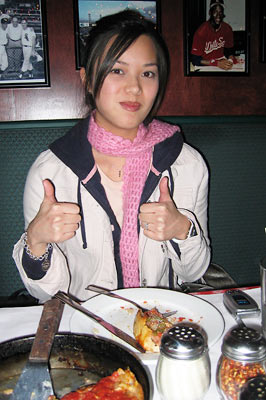 Geline enjoying her pizza with her thumbs